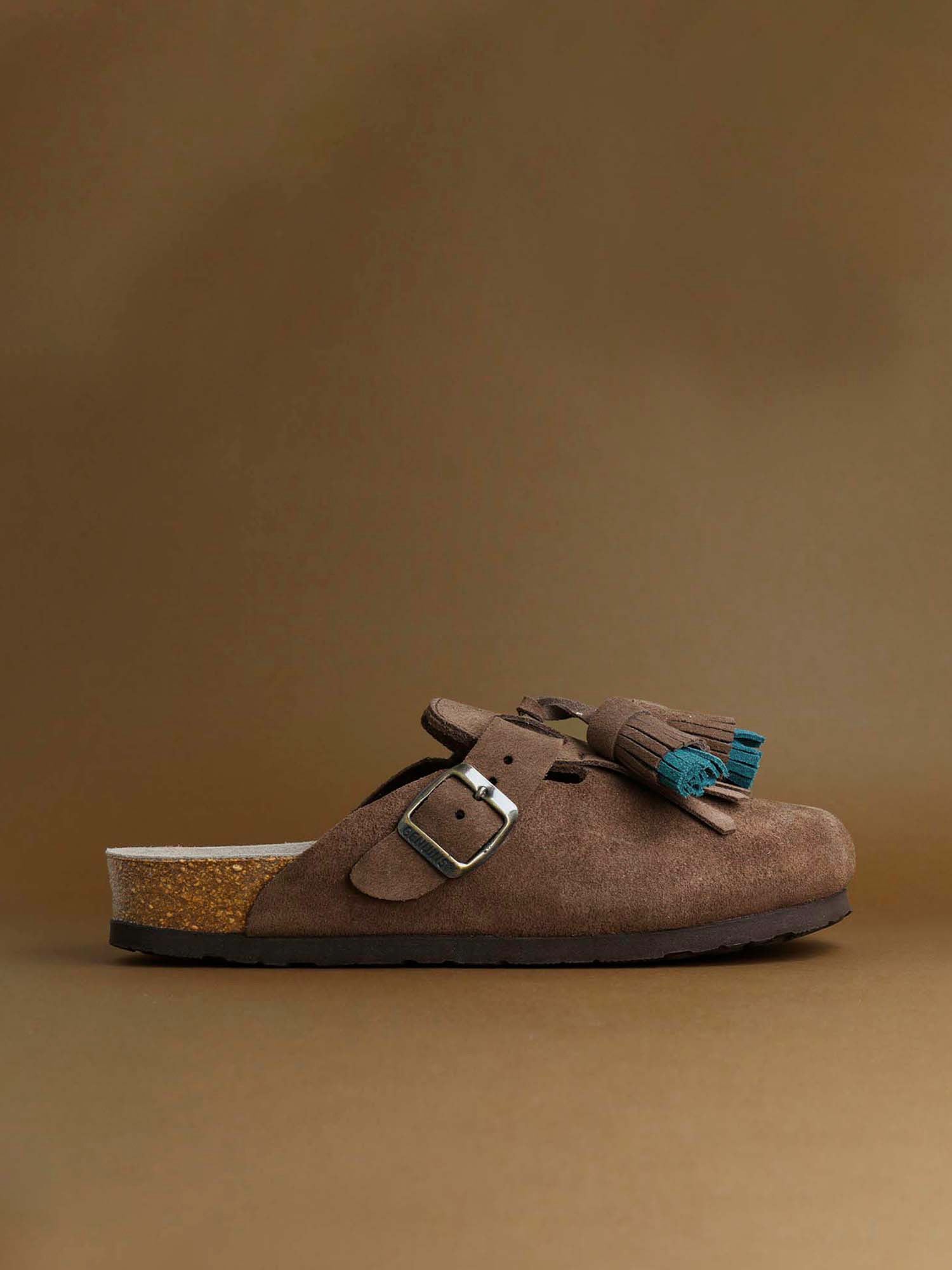 Zueco de la marca Genuins modelo Bora, en color marron oscuro con detalle de flecos y borla perfectos para el día a día, hechos en españa bajo una produccion sostenible y respetuosa con el medio ambiente.